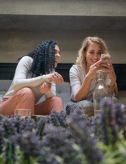 Two girls are looking at the phone and smiling in cafe
