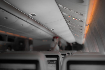 Fasten seat belt and no smoking signs in aircraft with stewardess blurred in background 