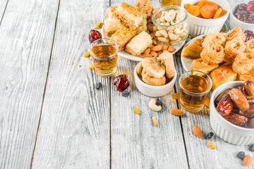 Set various Middle Eastern Arabian sweets - Turkish baklava, knafeh (kunaf), nuts, dried fruits and seeds. White wooden background, top view copy space