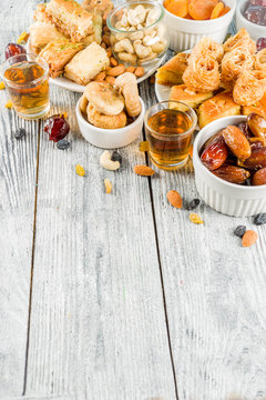 Set various Middle Eastern Arabian sweets - Turkish baklava, knafeh (kunaf), nuts, dried fruits and seeds. White wooden background, top view copy space