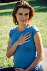 Young pregnant woman practicing yoga and meditation in the park