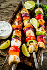 Grilled chicken skewers kebabs with vegetables, on rustic wooden table top view copy space