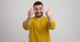 Excited man celebrating success by clapping and giving thumbs up gesture