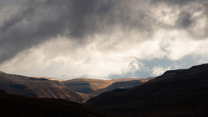 A snowy mountain top in the southern Drakensberg with storm clouds above.