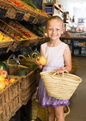 girl choosing apples in vegetable shop. on the signboard inscriptions in Catalan