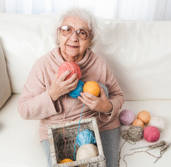 Smiling grandmother holding colorful knitting laces balls