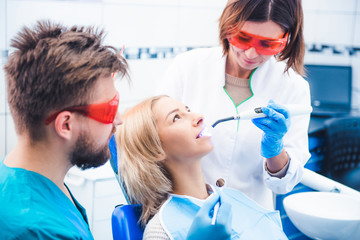 Dentists in red glasses lighting dental seal with ultraviolet lamp