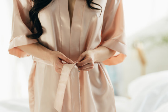 Cropped View Of Woman Untying Silk Robe At Home