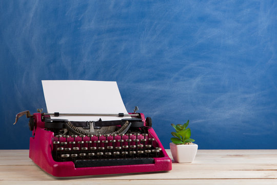 writer's workplace - crimson typewriter on blue blackboard background
