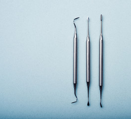 Metal dental tools on light blue background