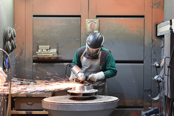 Arbeiter in der Industrie bearbeitet Werkstück aus Stahl mit einer Schleifmaschine // Worker in...
