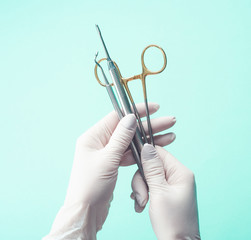 Hands in gloves holding medical tools on light background