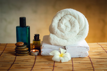 Obraz na płótnie Canvas Spa Oil Massaging Treatment and Skincare Concept., Component of Therapy Massage With Plumeria or Frangipani Flowers, Towel, Stones, Aroma Candle and Oil on The Desk.