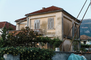 Old abandoned house with a red tile roof against the background of a mountain in a European resort town. Property for sale
