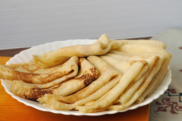 Several homemade pancakes on a white plate. Close-up.