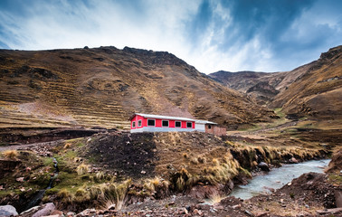 Pink flat house among Peruvian rocky mountains at the river bank