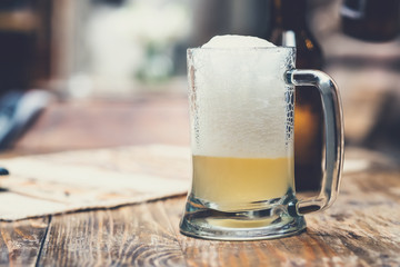 Glass cup of beer with foam on the wooden table