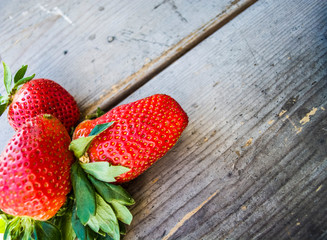 Fresh big and whole strawberry on a wooden background. Tasty summer berry. Vitamins. Useful healthy food.