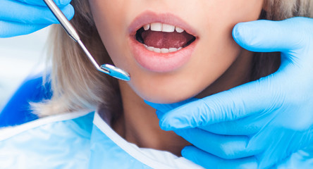 Closeup of dentist examinating blond girl with tool