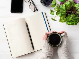 Top view of girl holding coffee mug and creating a plan at working place