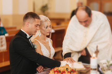 Beautiful couple in church. Newlyweds swear to each other to love forever. Happy bride and groom