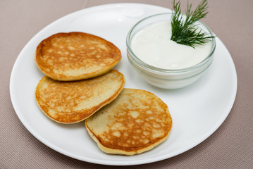 pancakes with sour cream in a white plate