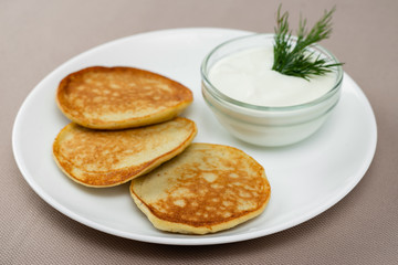 pancakes with sour cream in a white plate