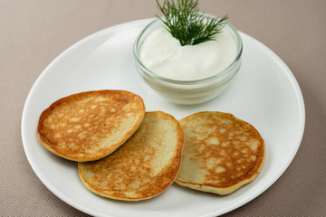 pancakes with sour cream in a white plate