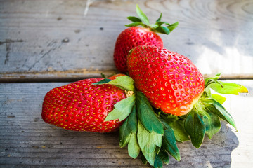 Fresh big and whole strawberry on a wooden background. Tasty summer berry. Vitamins. Useful healthy food.