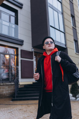 Free handsome independent man walking on street of modern luxury district with backpack in fashionable sun glasses. Freedom,traveller, leader man concept