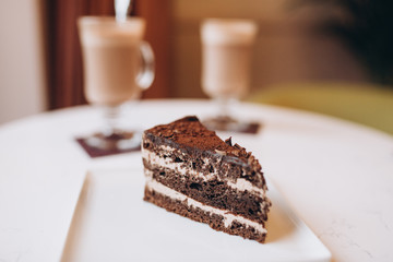 Two cups of cappucino with piece of cake in modern cafe