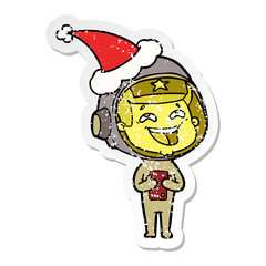 distressed sticker cartoon of a laughing astronaut wearing santa hat