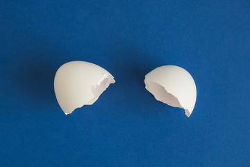 Broken egg isolated on blue background abstract.
