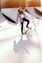 Cute mixed race teenage girl with curly hair and cap riding skateboard at skate park.