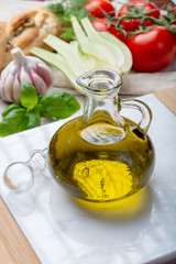 Virgin natural olive oil is glass bottle, served with traditional Mediterranean food