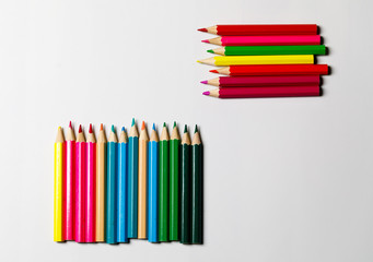 Multi-colored pencils for drawing on a white table. Ready photo background.