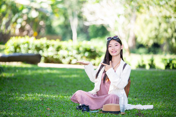 Female tourists who are smiling bright, happy sitting on the grass