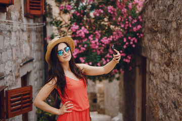 beautiful girl in a bright dress and a hat sit in a summer sunny city