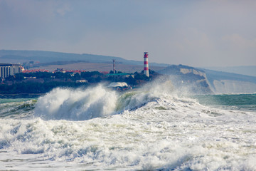 Beautiful and dangerous storm waves on the background of the Gelendzhik lighthouse. Resort...