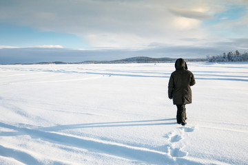 Fototapeta na wymiar Eine Frau geht auf dem zugefrorenem Inarisee