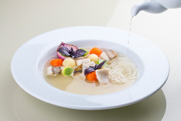 Fish soup with vegetables in the original serving