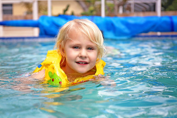 Toddler Child Wearing Inflatable Life Jacket Learning to Swim in Backyard Family Pool