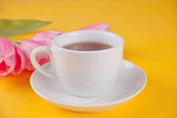 A cup of tea and pink tulips on the table