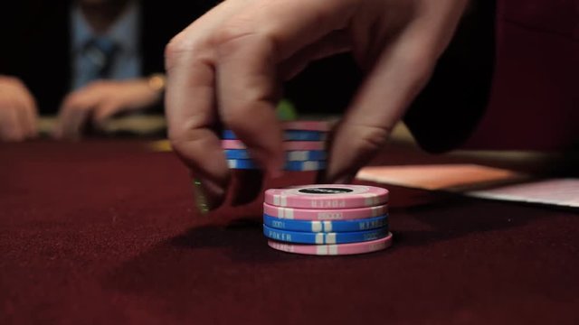Casino: dealer shuffles the poker chips and performing trick with chips use one hand. Hand close-up.