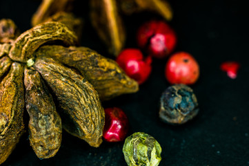 Star anise and multi-colored balls fragrant peppers on a black background, close-up, macro