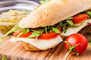 Toasted panini with ham, cheese and arugula sandwich on cutting board