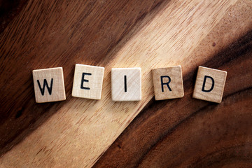 Word Weird Spelled out in Wooden Letter Blocks on Dark Acacia Wood Background.