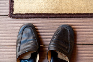 Leather slippers stand in front of carpet