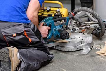 Occupation concept - construction worker operates a parquet cutting machine on the floor.