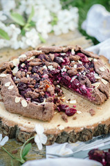 Chocolate cherry galette or pie on a wooden board. Spring or summer picnic in nature.